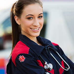 Smiling female paramedic in a red and black uniform with a stethoscope, representing verified emergency medical professionals for healthcare contact lists.